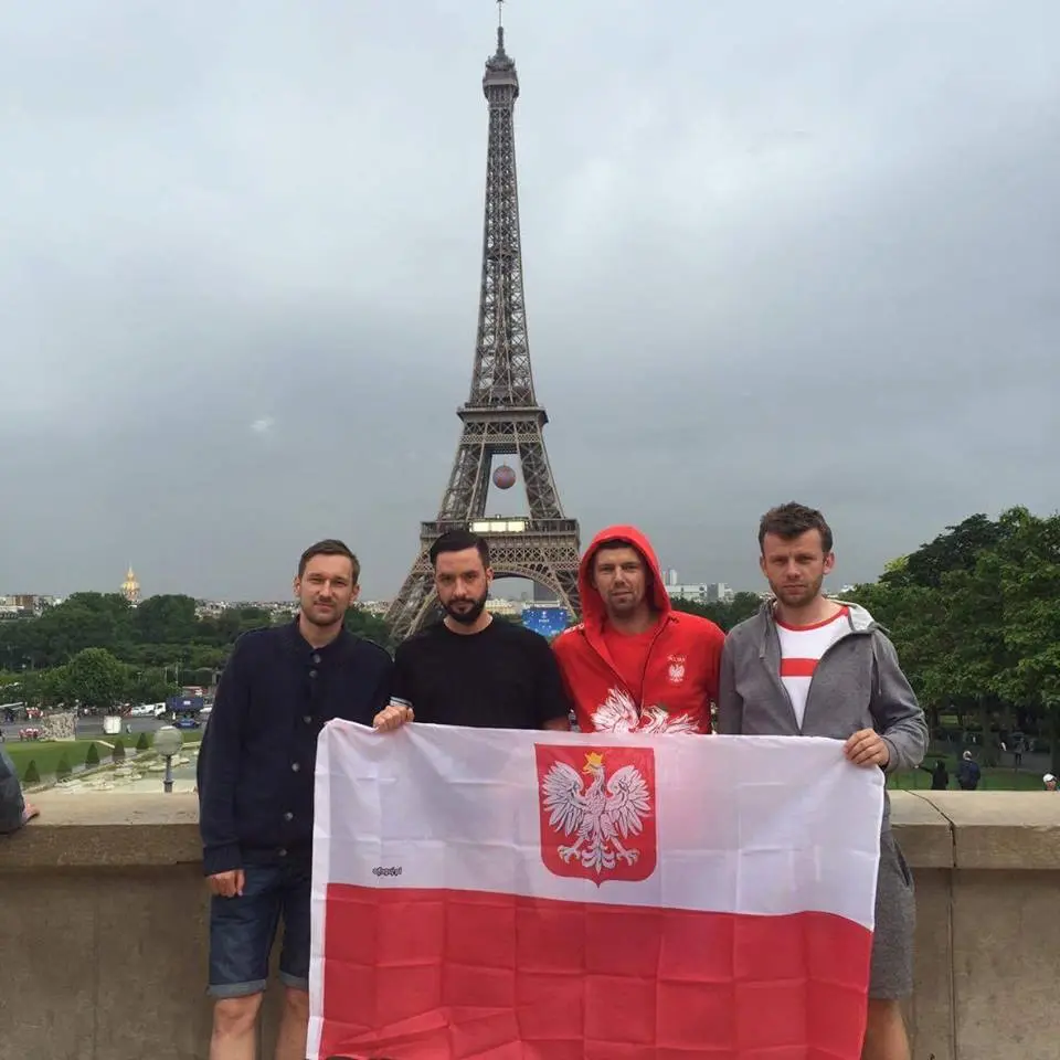 Kibice z flagą Polski z orzełkiem przed wieżą Eiffla